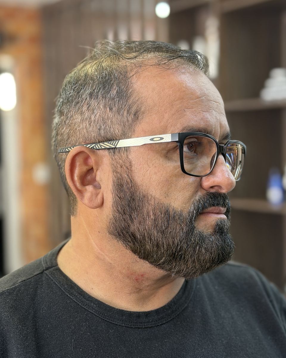Cliente de óculos com barba cheia desenhada e cabelo curto